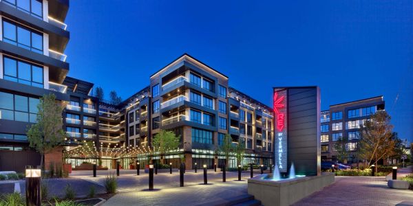 Modern apartment complex with illuminated signage and outdoor lighting at dusk.