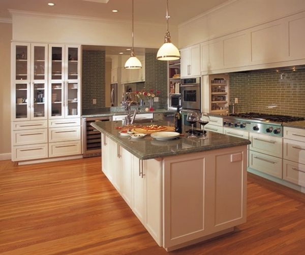 Kitchen with white shaker cabinets and warm-toned wide-plank hardwood flooring by Floors N More