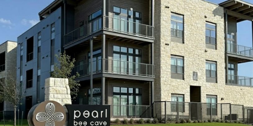 Modern apartment building with a Pearl Bee Cave sign.
