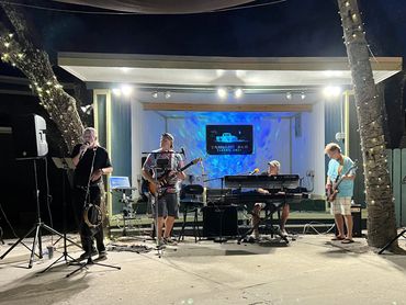 A classic rock band performs live on an outdoor stage at night.