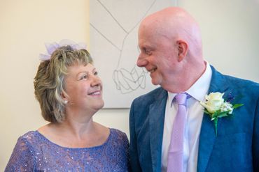 A joyful older couple gazing lovingly at each other, dressed for a special occasion.