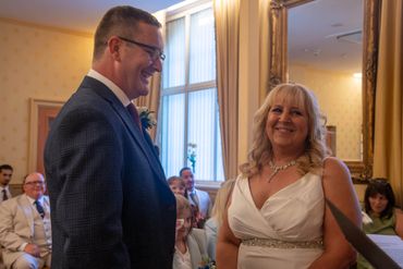 A joyful couple exchanging smiles during their wedding ceremony indoors.