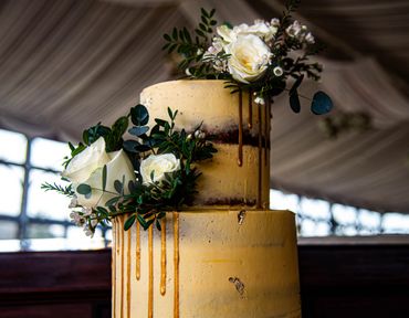 Elegant two-tier cake with white roses and greenery decoration.