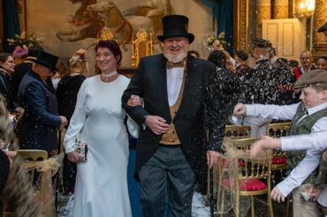Newlyweds joyfully walk down the aisle amidst a shower of confetti.