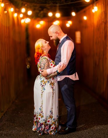 Couple sharing a joyful moment under string lights in an intimate setting.