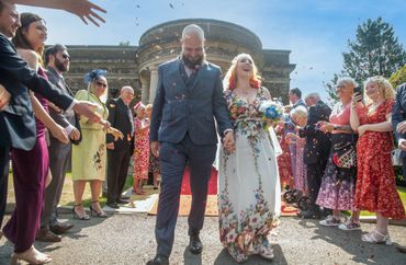 Newlyweds joyfully walk down the aisle as guests shower them with petals.