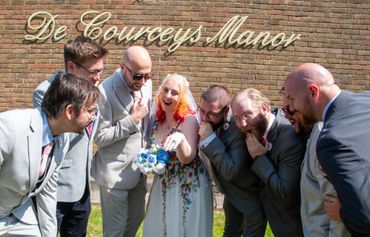 Bride shows her ring as groomsmen react excitedly outside De Courceys Manor.