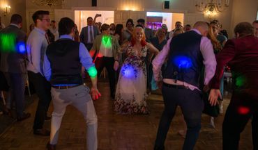 People dancing joyfully at an indoor party with colorful lights.