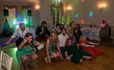 Group of people dancing and having fun on a dance floor with colorful lights.