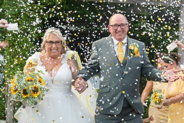 Newlyweds celebrate with confetti and sunflowers on their wedding day.