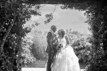 A bride and groom share a loving moment framed by lush greenery.
