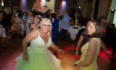 Bride and guests joyfully dancing at a wedding reception.