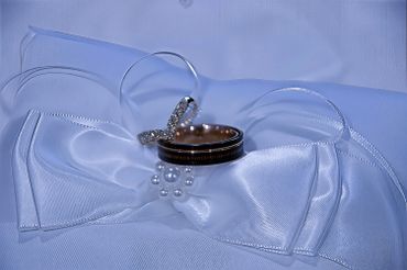 Elegant wedding rings on delicate white fabric with pearls and rhinestones.