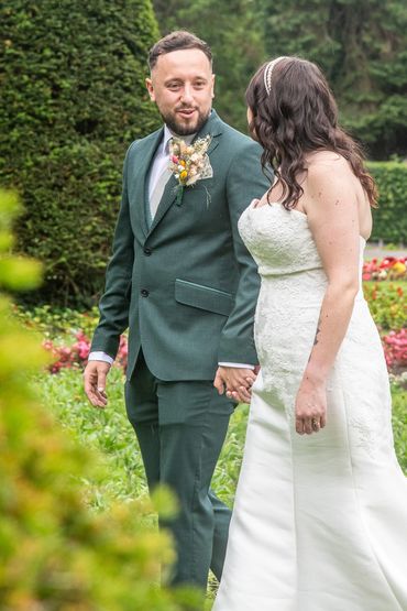 A couple holding hands during a wedding ceremony in a garden.