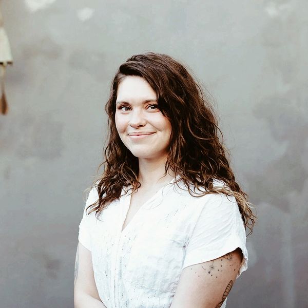 Woman with curly hair smiling, wearing white shirt.
