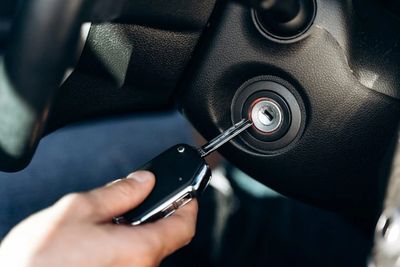 Hand inserting car key into ignition to start vehicle.