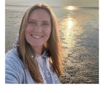 Woman smiling at the beach during sunset.