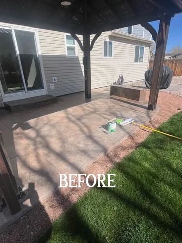 A backyard patio area before renovation with a covered pergola and some painting supplies.