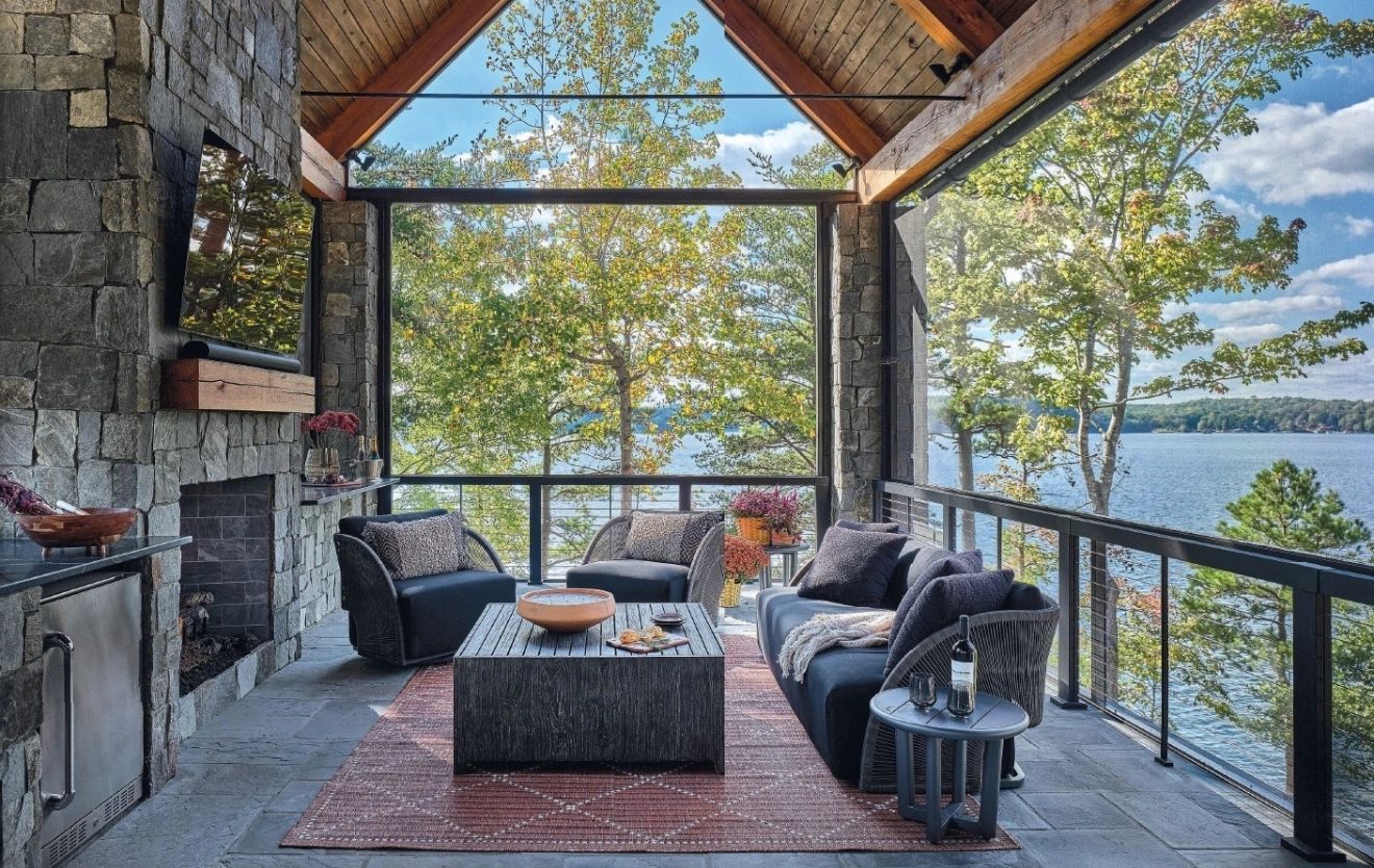 Luxurious lakeside outdoor living space featuring a stone fireplace, stylish seating, and stunning waterfront views — perfect for upscale relaxation and entertaining.