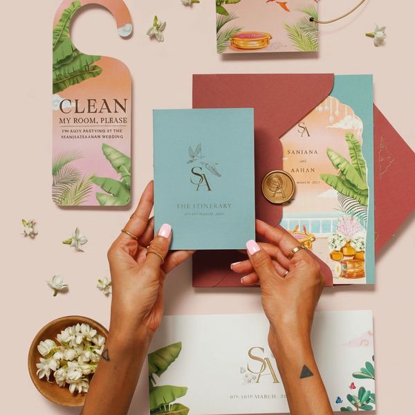 Elegant tropical-themed wedding stationery set with hands holding an itinerary card.