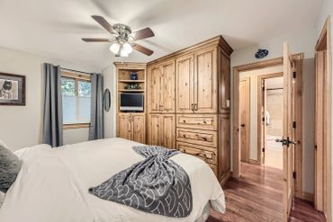 Cozy bedroom with wooden furniture and a ceiling fan.