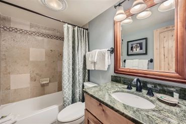 Cozy bathroom with granite countertop and patterned shower curtain.