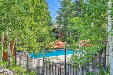 Outdoor pool surrounded by trees and umbrellas in a serene setting.