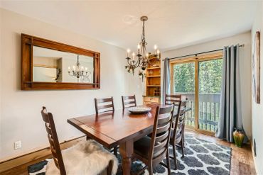 Cozy dining room with wooden furniture and large window overlooking greenery.
