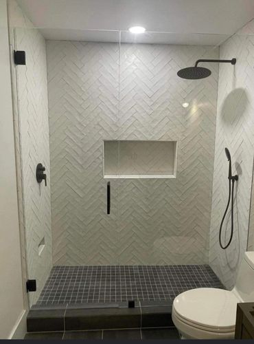 Modern bathroom shower with glass door and black fixtures.