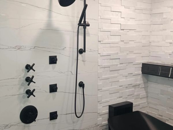 Modern bathroom with black fixtures, textured white walls, and a sleek black bathtub.