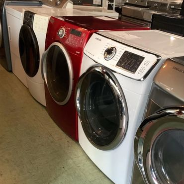 Front-loading washing machines in various colors lined up indoors.