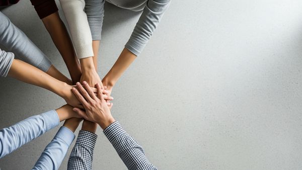 A diverse group of people joining their hands together in a show of unity and teamwork.