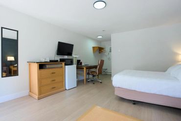 Bright, minimalist hotel room with wooden furniture and white bedding.