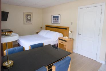 Simple hotel room with a bed, small table, and chairs.