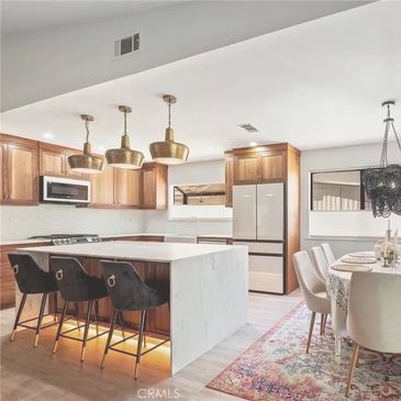 Modern kitchen and dining area with wooden cabinets and elegant lighting.