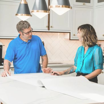 Two people discuss plans over blueprints in a modern kitchen.