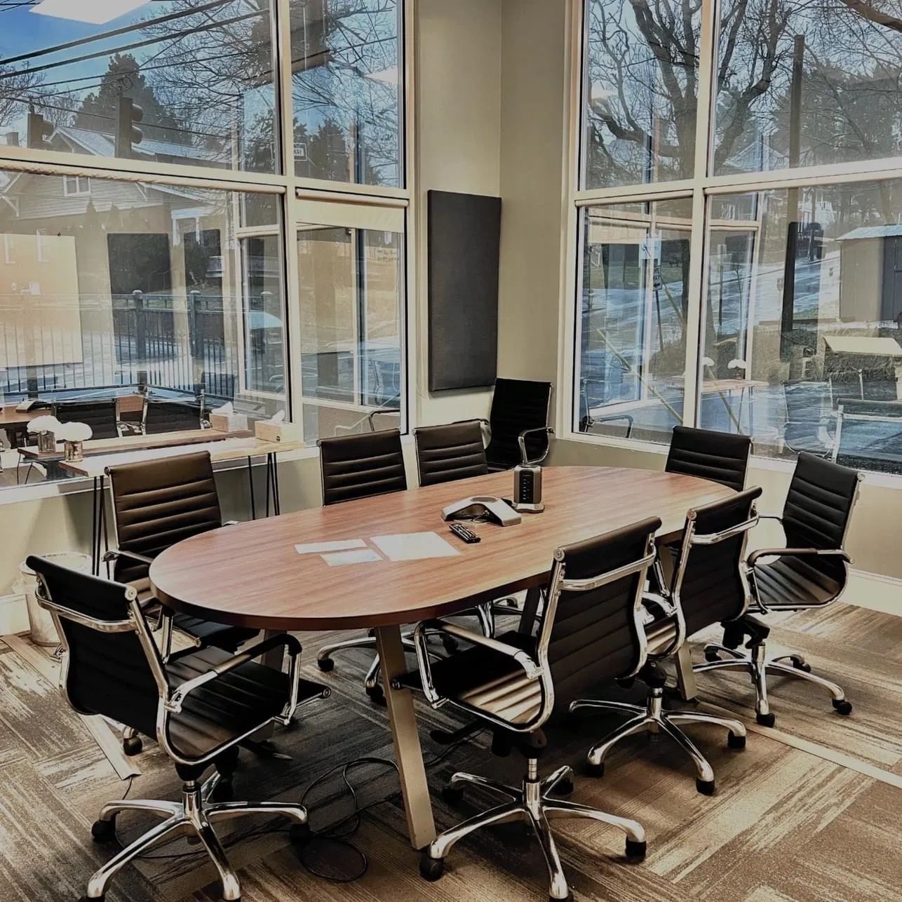 Modern conference room with black chairs and a wooden table.