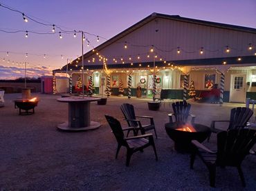 Outdoor seating with fire pits and festive holiday lights at dusk.