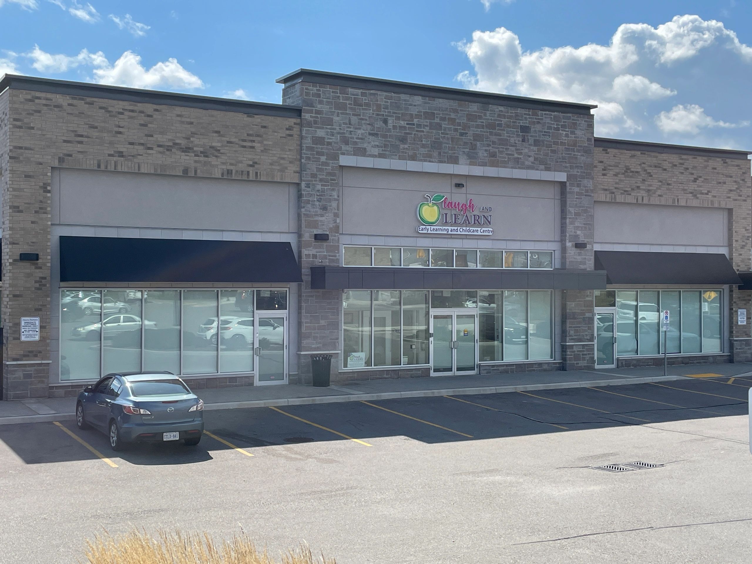 A building with a storefront sign that reads, "Laugh and Learn Early Learning and Childcare Center".