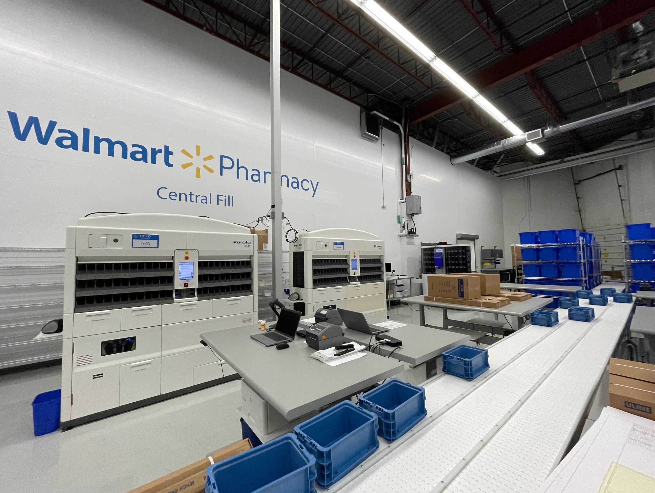 A large room with machines and a large wall sign that reads, "Walmart Pharmacy - Central Fill".