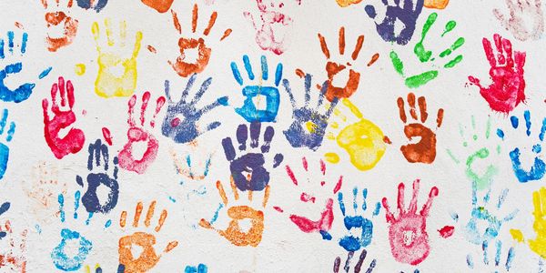 A white wall with many multi-color, painted handprints