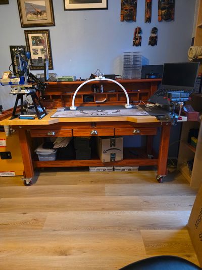 A wooden workbench with tools and a laptop in a home workshop.