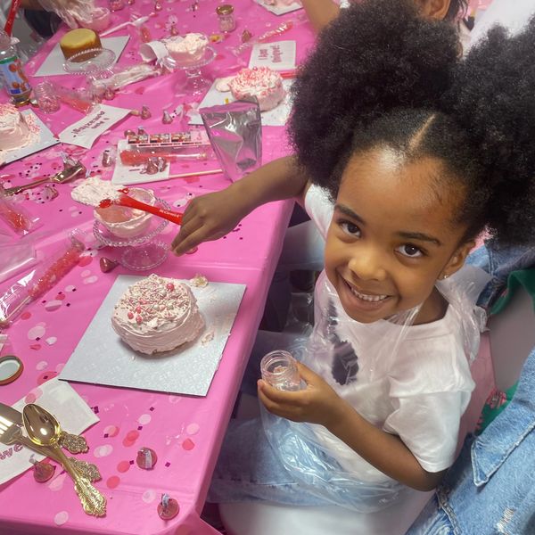 Girl decorating cake at a party with pink decorations.