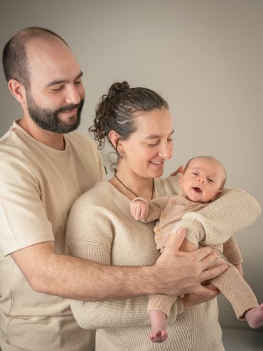 Happy parents lovingly hold their newborn baby dressed in cozy knitwear.