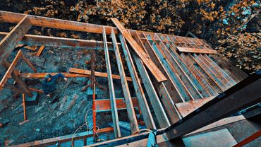 A person working on wooden framing outdoors surrounded by autumn foliage.