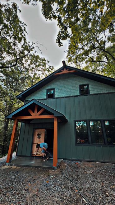 Person cleaning porch of a modern cabin in the woods.