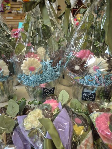 Gift baskets with flower-shaped chocolates wrapped in clear plastic and green ribbons.