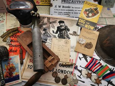 A collection of World War II memorabilia including medals, badges, manuals, and wartime posters.