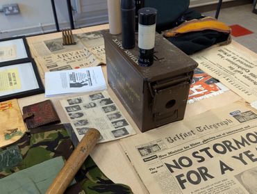 Historical artifacts and newspapers from a conflict era displayed on a table.