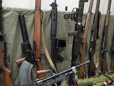 A collection of vintage rifles and military firearms displayed against a green backdrop.